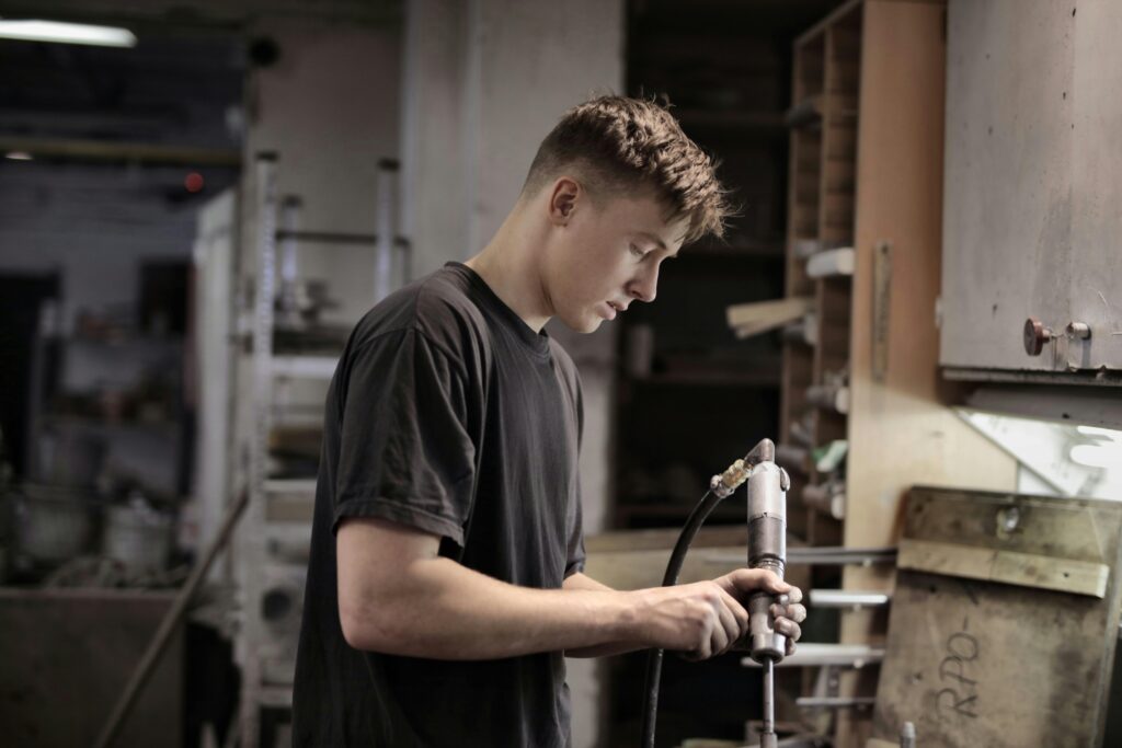 pexels-photo-3846390-3846390 Side view of young male worker using pneumatic tool for handling detail in workshop